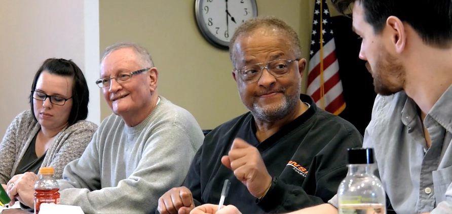 Five adult people talking at a table