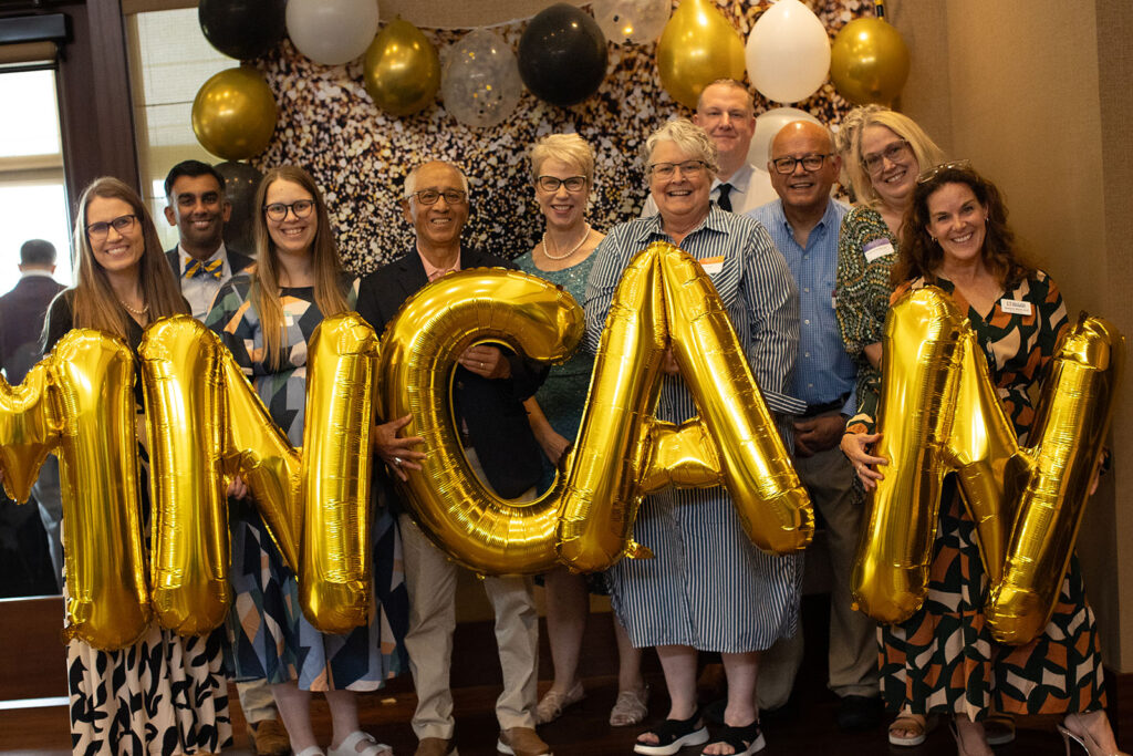 People standing while holding balloons that spell out the word MNCAN
